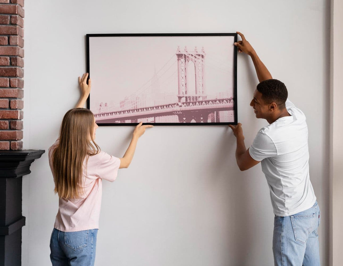 couple hanging an acrylic mounted photo on a wall using careful placement