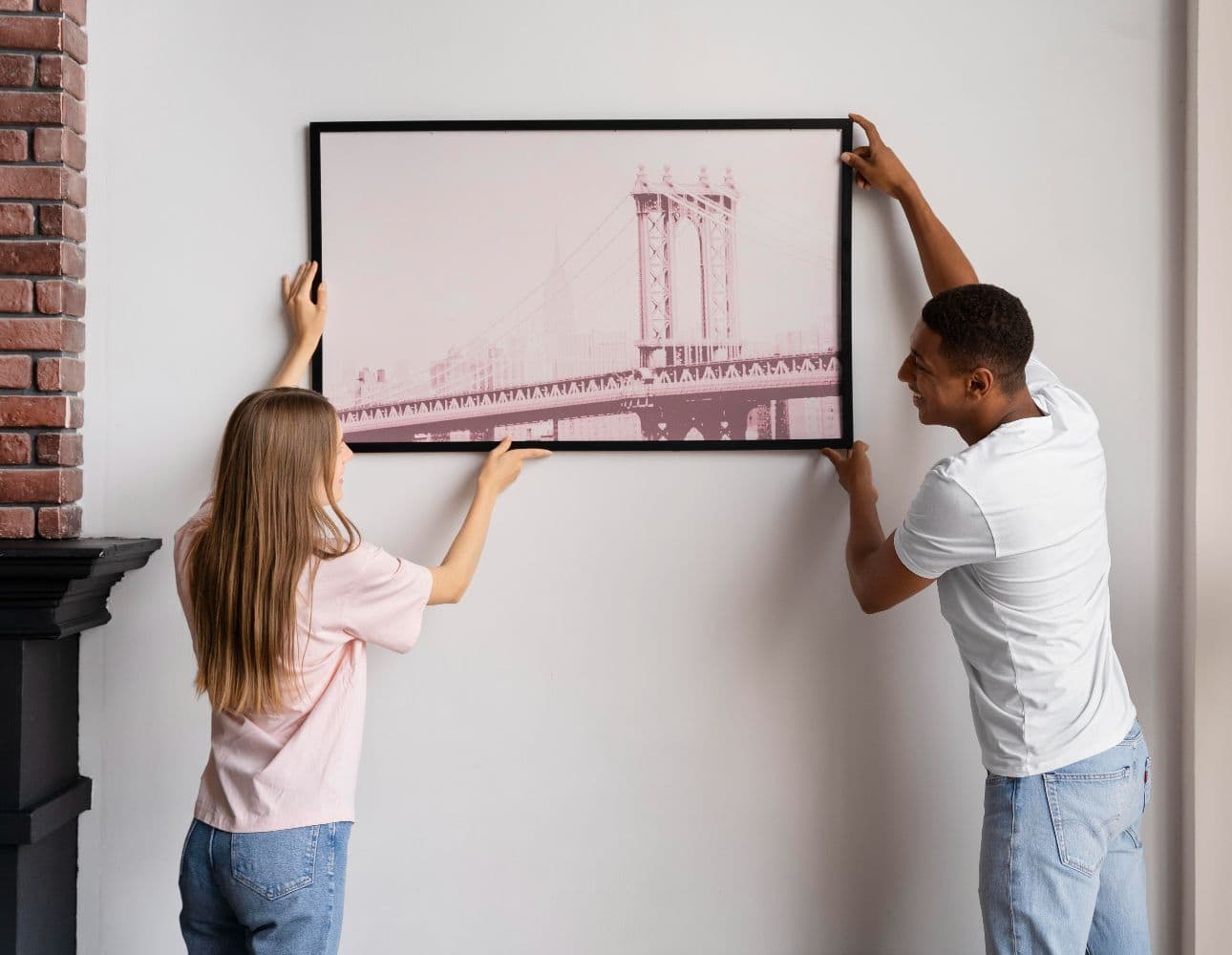 couple hanging an acrylic mounted photo on a wall using careful placement